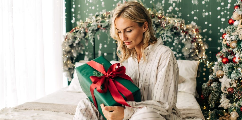 Woman excitedly opening a Christmas gift with a joyful smile