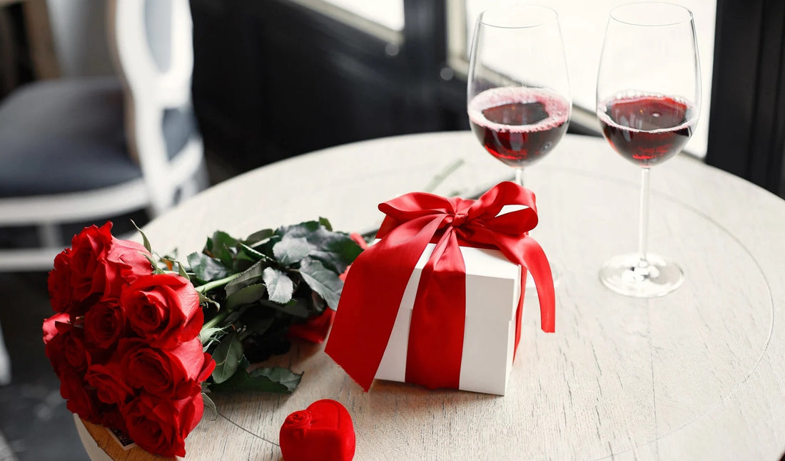 "Valentine’s Day gift on table with wine and flowers, featuring a romantic setting.