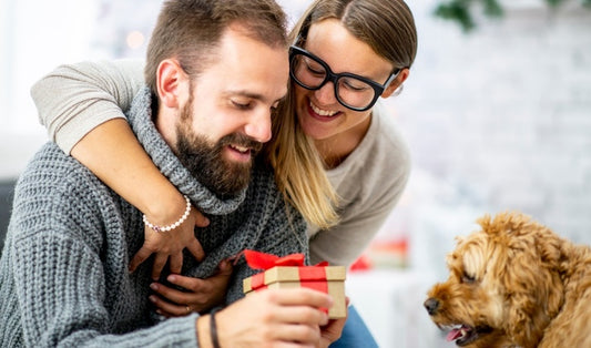 Happy woman gifting her man a personalized gift with a smile, celebrating a special moment together.