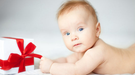 Baby lying near a beautifully wrapped gift with soft lighting, perfect for capturing a heartwarming moment of innocence and joy.