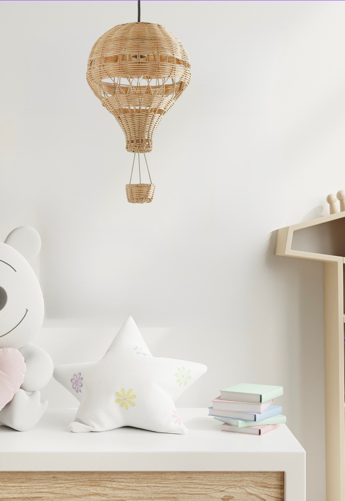 A hand-woven bamboo hot air balloon lamp hanging above a baby's dresser.
