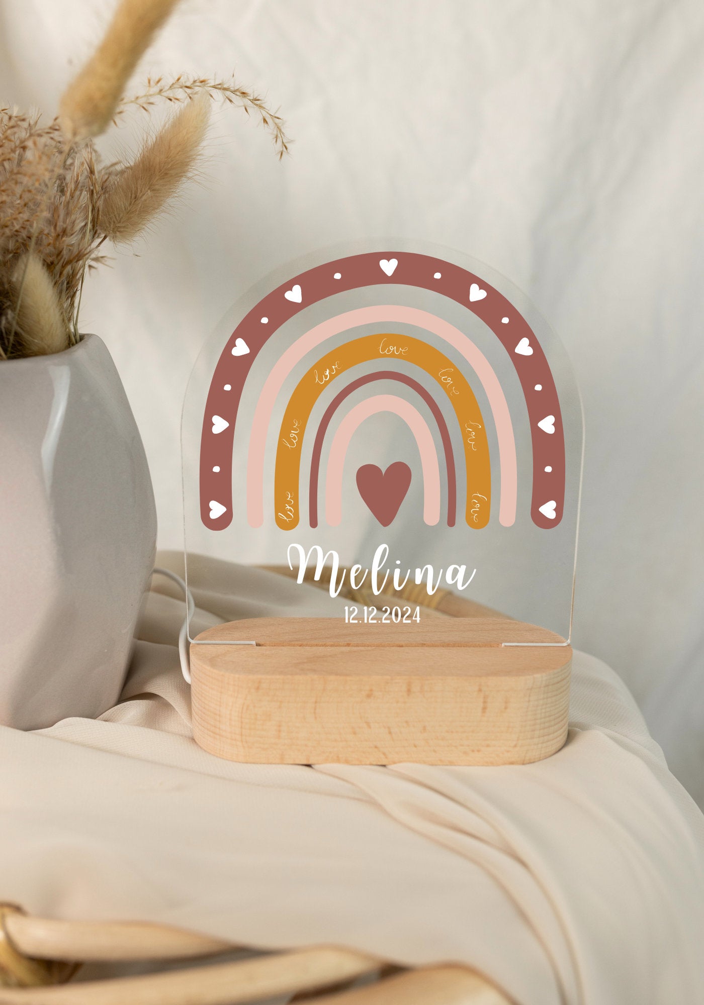 Children's night light featuring a rainbow motif and personalized with a name and birth date, captured in daylight with cloe-up view.