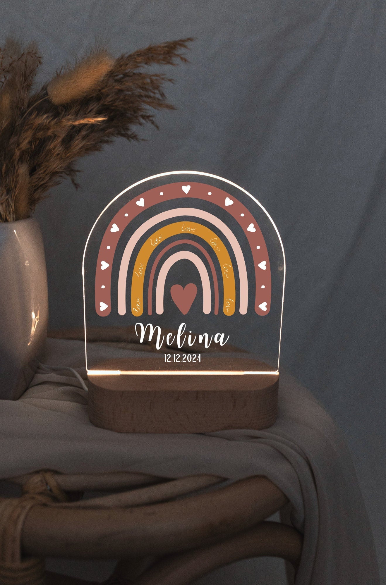 Children's night light featuring a rainbow motif and personalized with a name and birth date, captured in low light against a boho-style background.