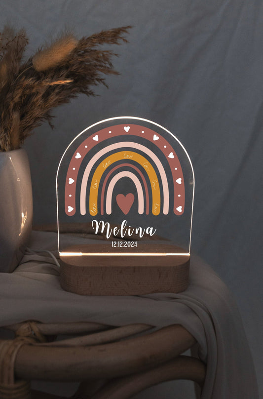 Children's night light featuring a rainbow motif and personalized with a name and birth date, captured in low light against a boho-style background.