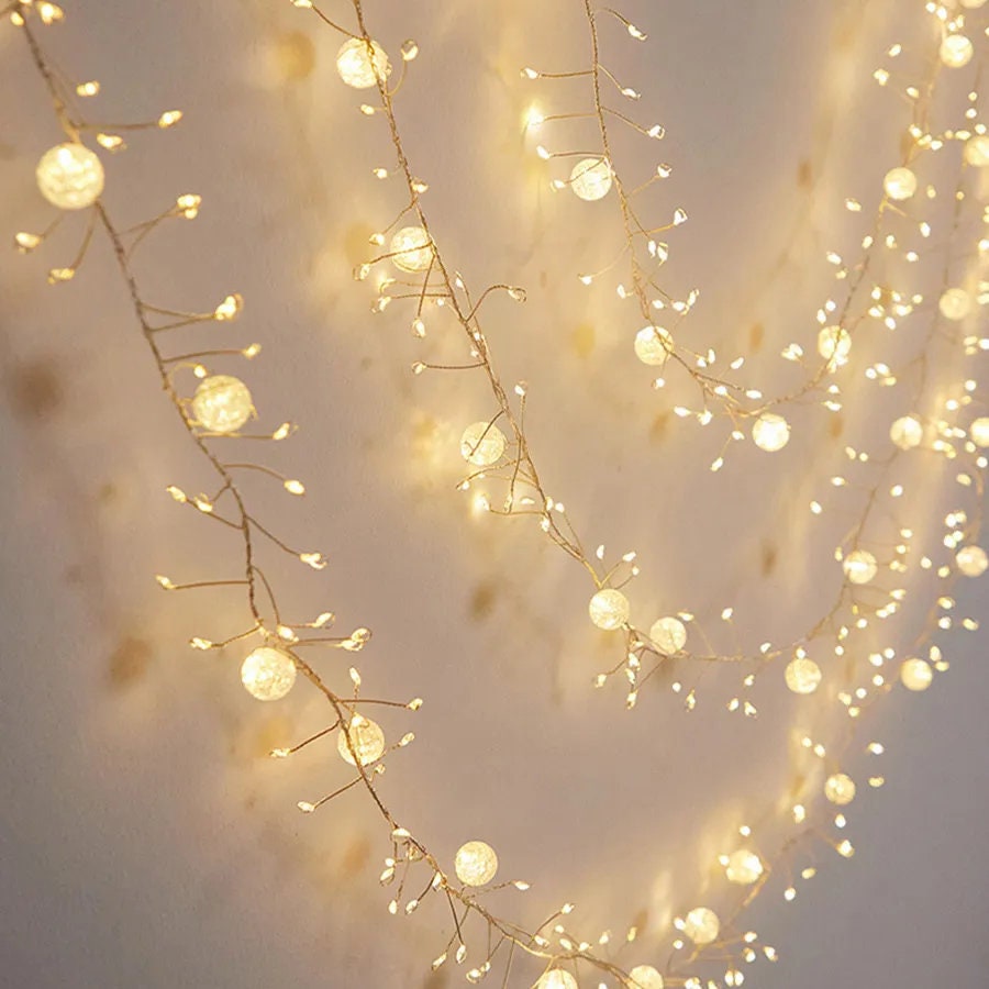 Fairy lights with crackling crystals hang decoratively on a wall, casting a warm white glow through their spherical bulbs.