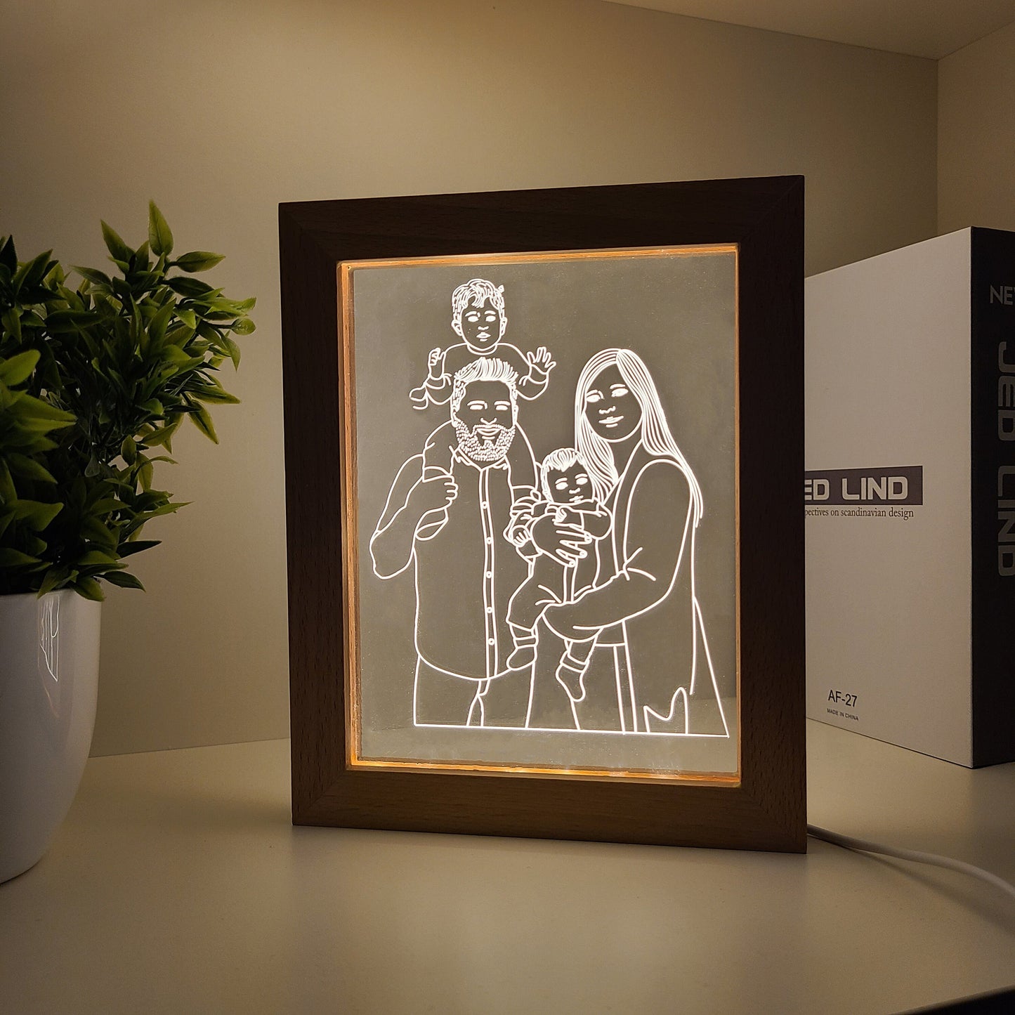 Personalized family photo frame lamp on a bookshelf desk in dark light.