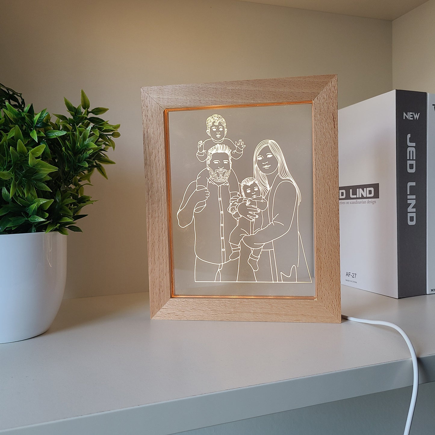Personalized family photo frame lamp on a bookshelf desk in daylight.