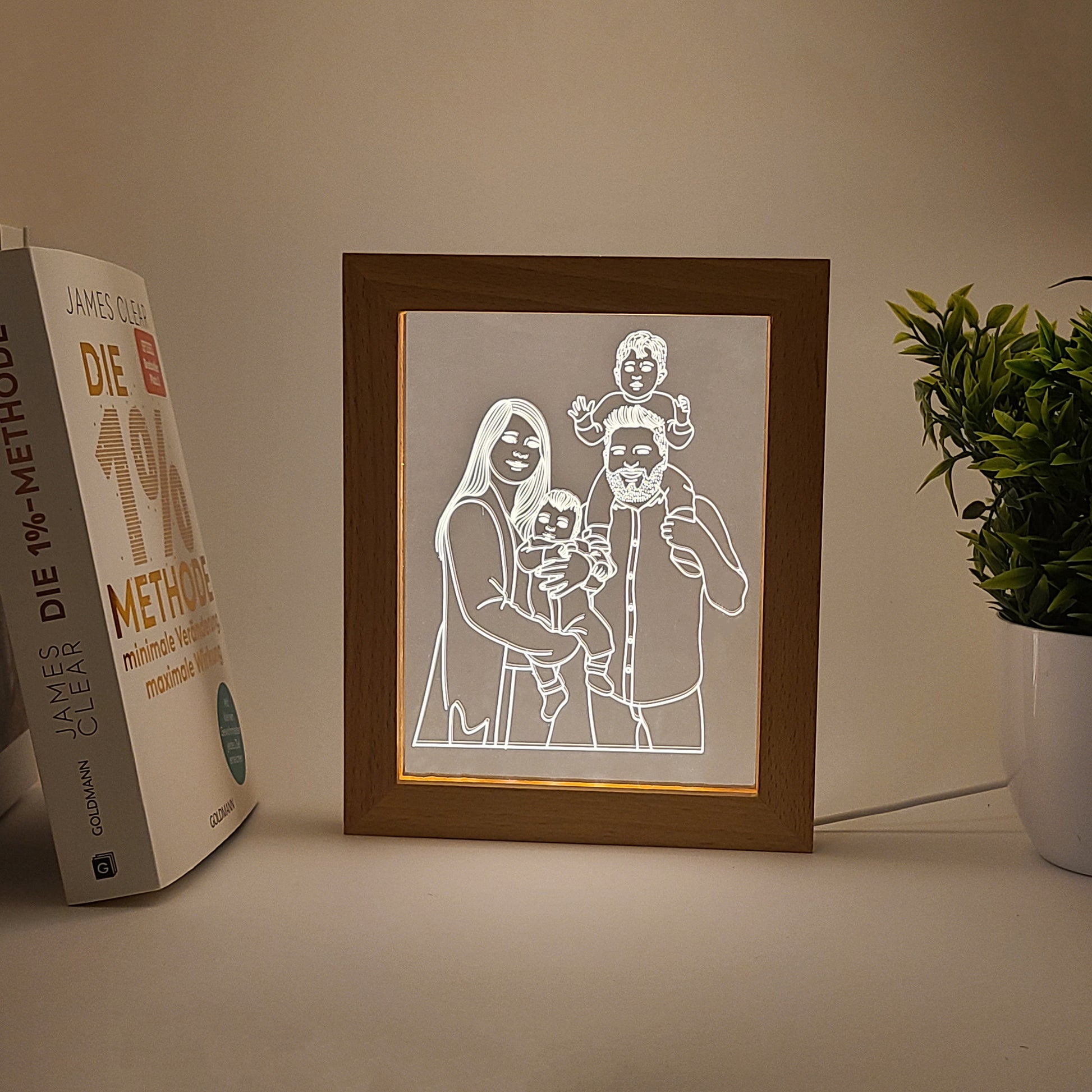 Personalized family photo frame lamp on a desk, captured in low light.