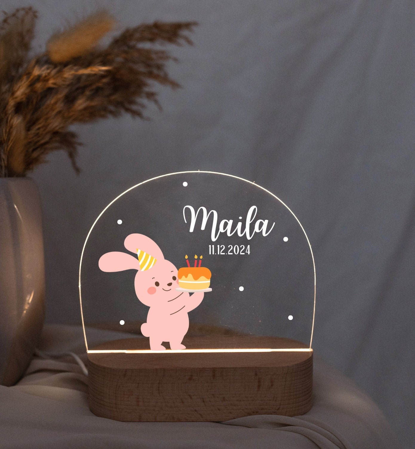 Pink baby night light featuring a rabbit motif, captured in low light with a close-up view against a boho-style background.